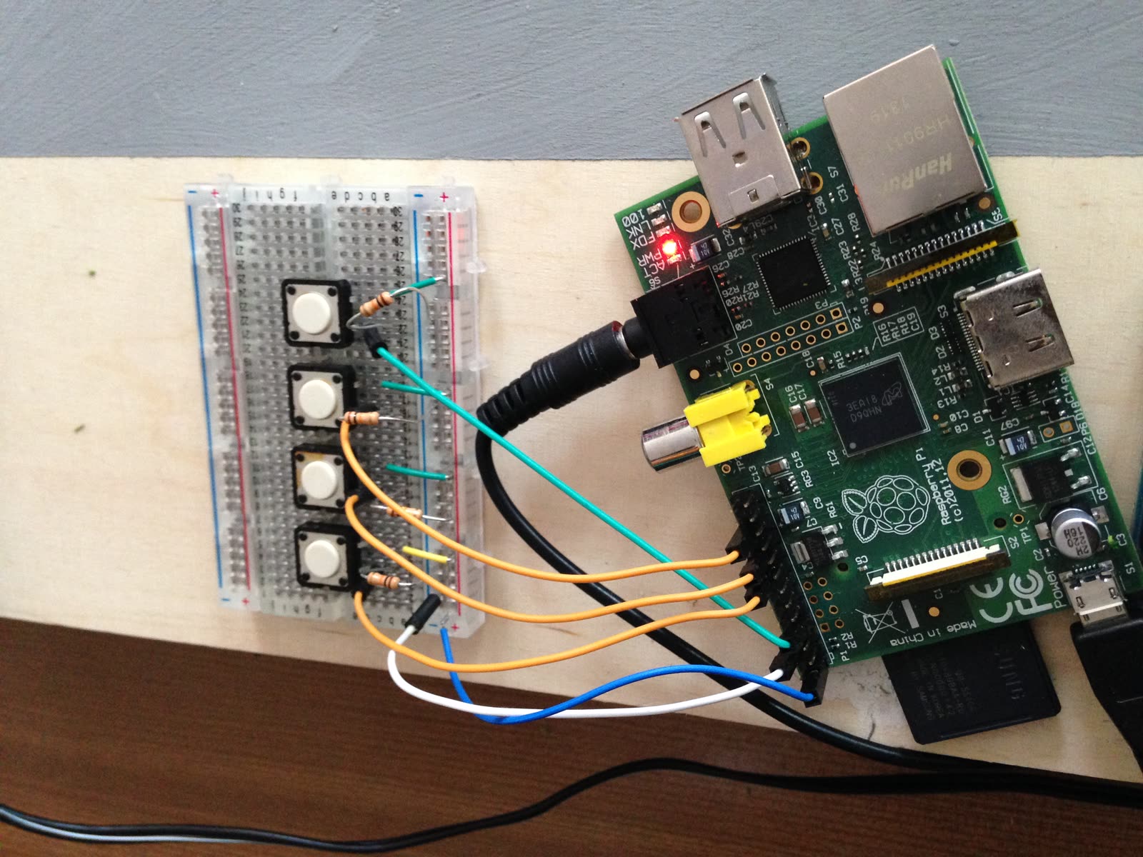 Raspberry Pi mit vier Tastern auf einem Steckbrett und bunten Kabeln