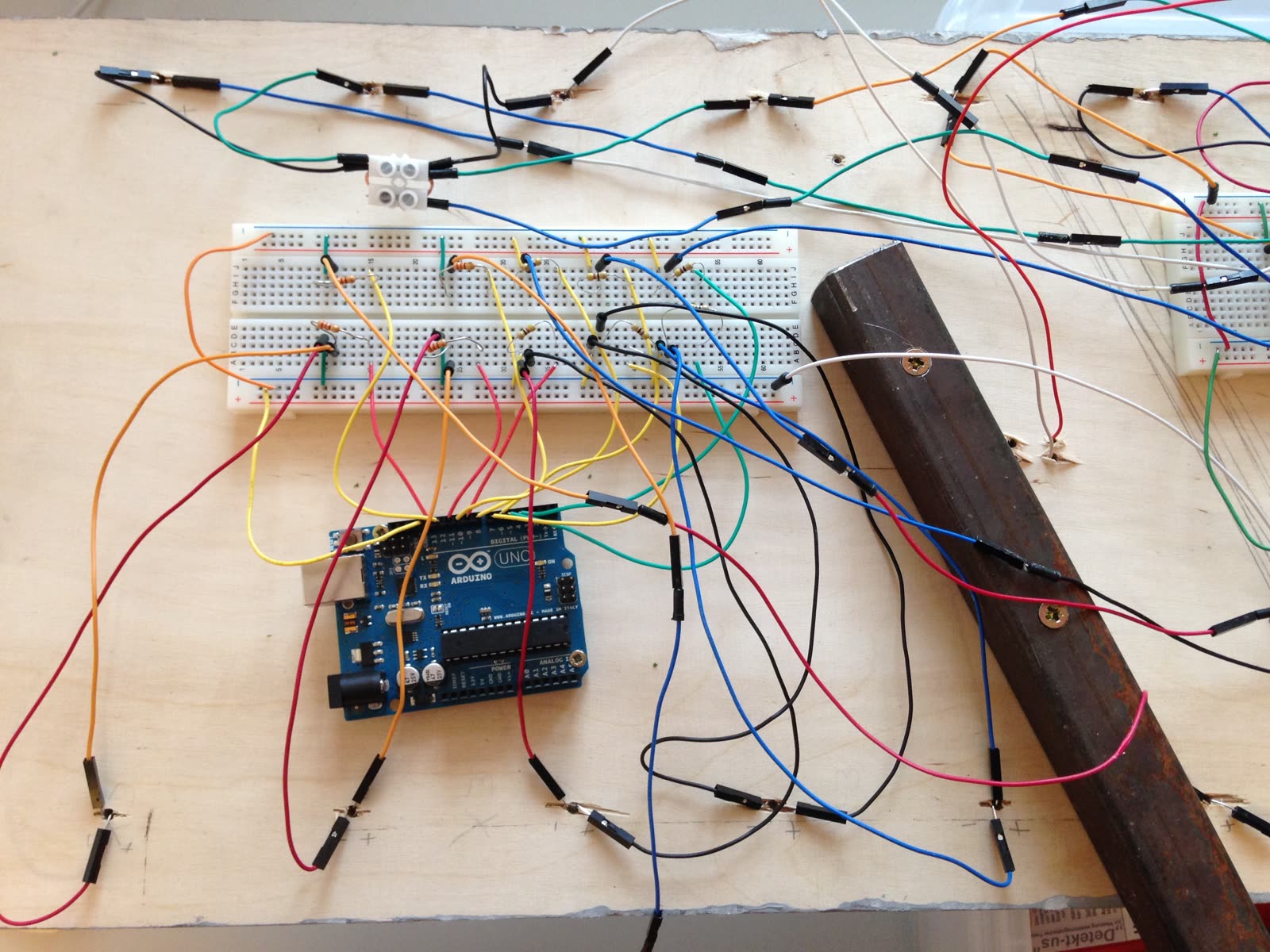 Arduino und Steckbrett mit vielen bunten Kabeln auf einer Holzplatte