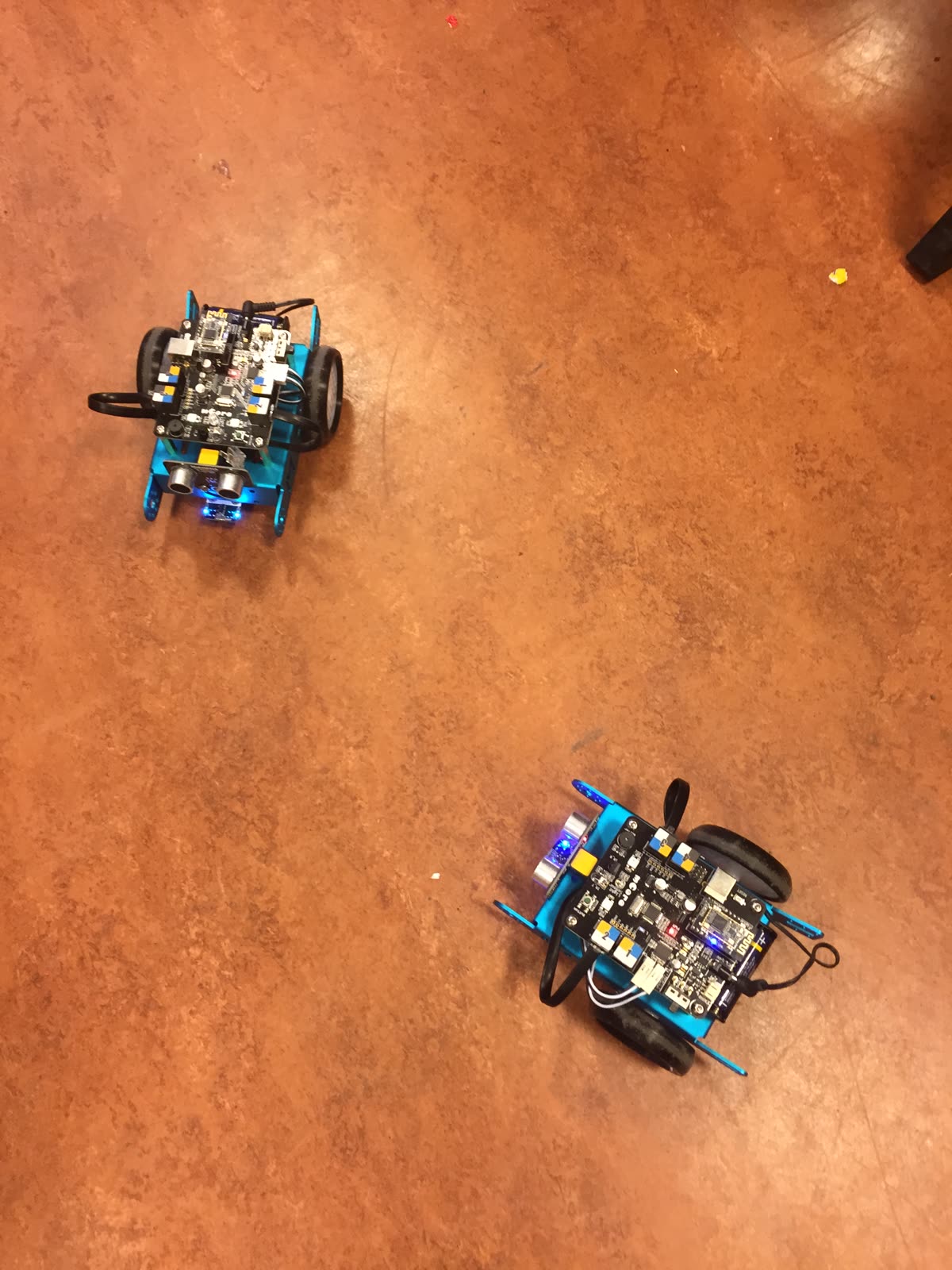 Zwei fertige mBots auf einem Holzboden von oben