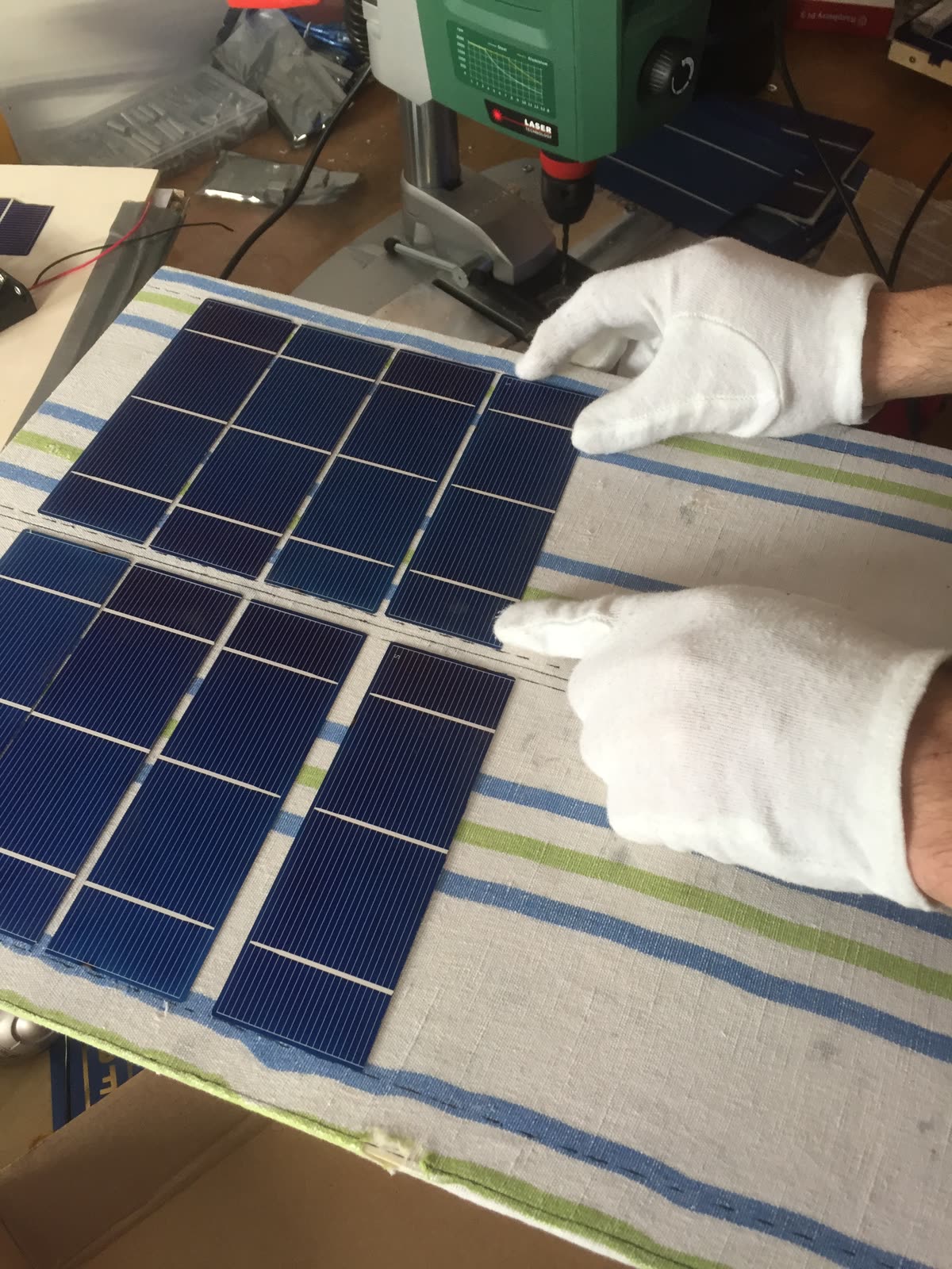 Mehrere Solarzellen werden mit Handschuhen auf einem Tuch zu einem Modul angeordnet