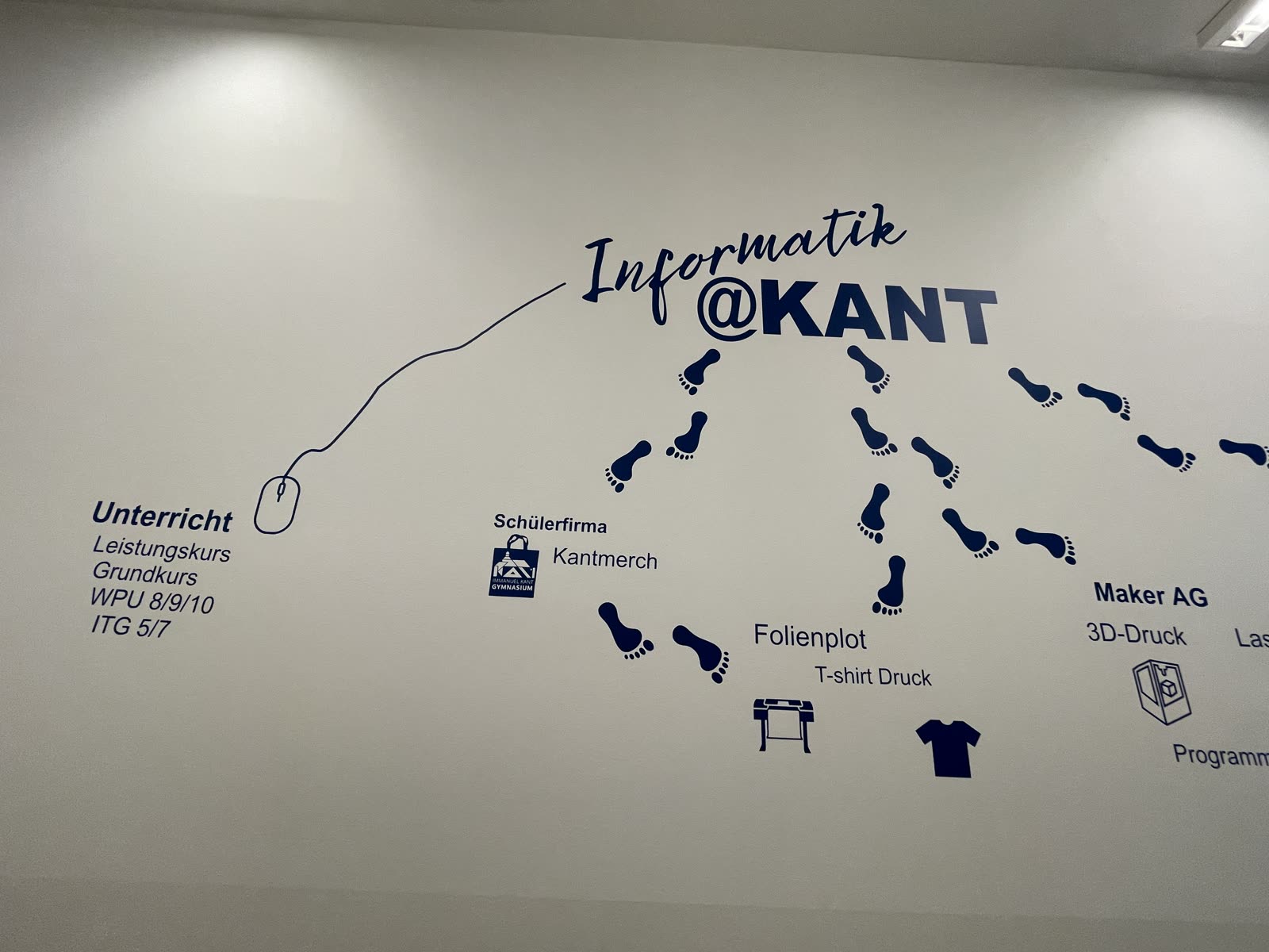 Wandgrafik „Informatik@Kant“ mit Fußspuren, die zu Unterricht, Schülerfirma, Folienplot und Maker-AG führen