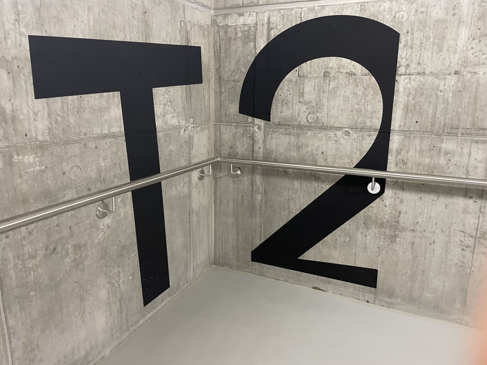 Große schwarze Etagenkennzeichnung „T2“ an der Betonwand im Treppenhaus